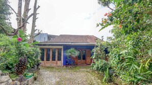 A courtyard with a stone pathway leading to a wooden house with a tiled roof. - OYO Homes 91157 Desa Wisata Bendosari Kendal (Bendosari)