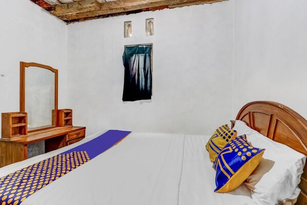 A bedroom with a wooden bed, a nightstand, a mirror, and a wall-mounted painting.