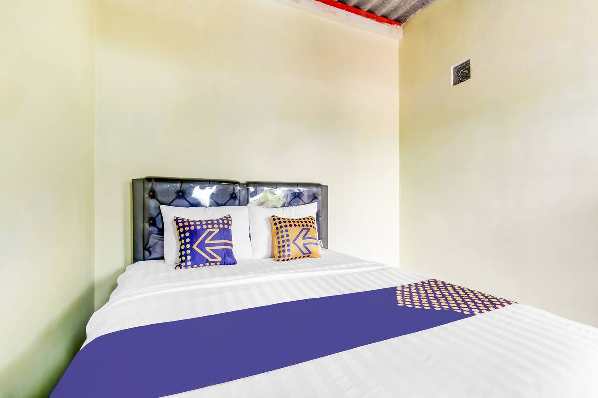 A bed with a white and blue bedspread, two pillows with geometric patterns, and a headboard with a textured design.