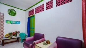 A room with purple sofas, a small table, a bench, and a decorative wall piece. - Hotel O Homestay Bude Sri (Batam)