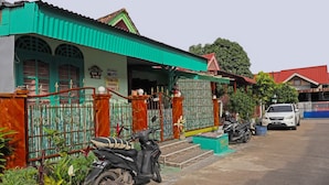 A house with a green roof, a gated entrance, and a parked scooter. - Hotel O Homestay Bude Sri (Batam)