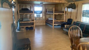 A rustic cabin with wooden bunk beds, a dining table, and a sofa. - Retreat to nowhere. (Petrolia)