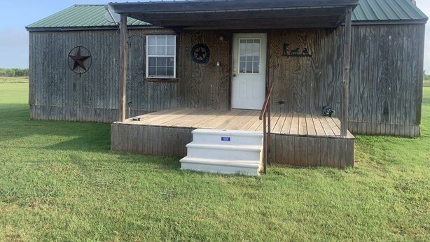 A rustic wooden building with a porch, a door, and a small window. - Retreat to nowhere. (Petrolia)