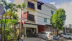 A multi-story building with a commercial ground floor, a balcony, and a tree in front. - Hotel O Bumi Merpati Residence (Makassar)