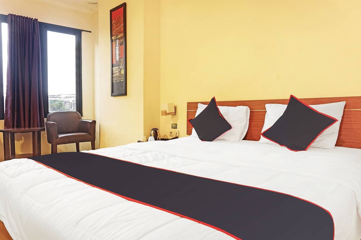 A hotel room with a large bed, a wooden headboard, and a view of the city through the window.