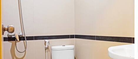 A small bathroom with a toilet, a sink, and a shower.