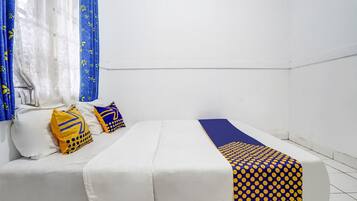A room with a bed, a blue and yellow patterned blanket, and a white pillow with a yellow design.