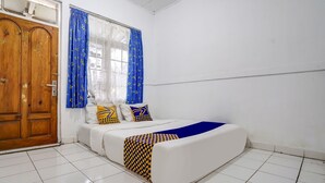 Un dormitorio con cama, puerta de madera y ventana con cortinas azules.