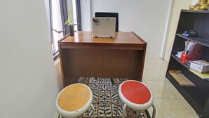 A room with a desk, two chairs, a laptop, a bookshelf, and a patterned floor.