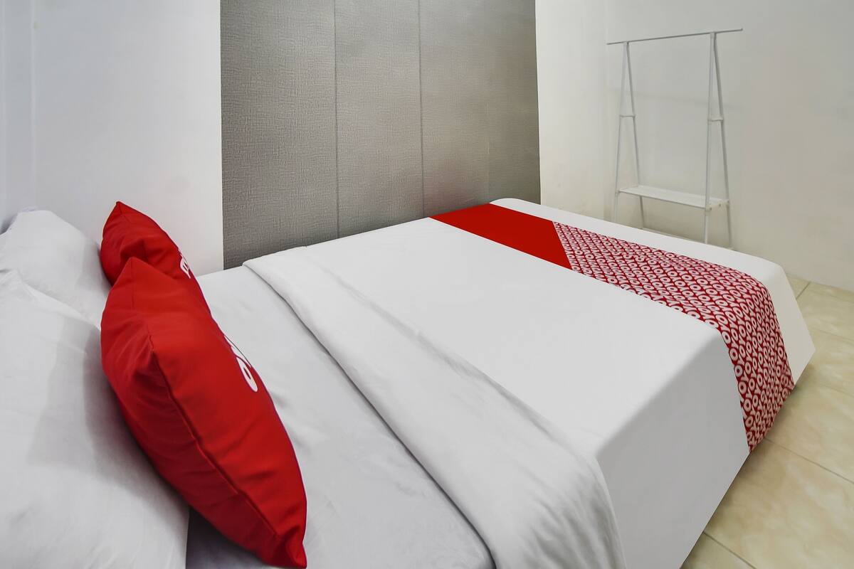 A hotel room with two beds, each with white bedding and red accents.