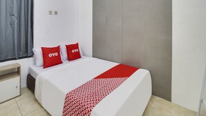 A neatly made bed with white bedding and a red and white patterned throw.