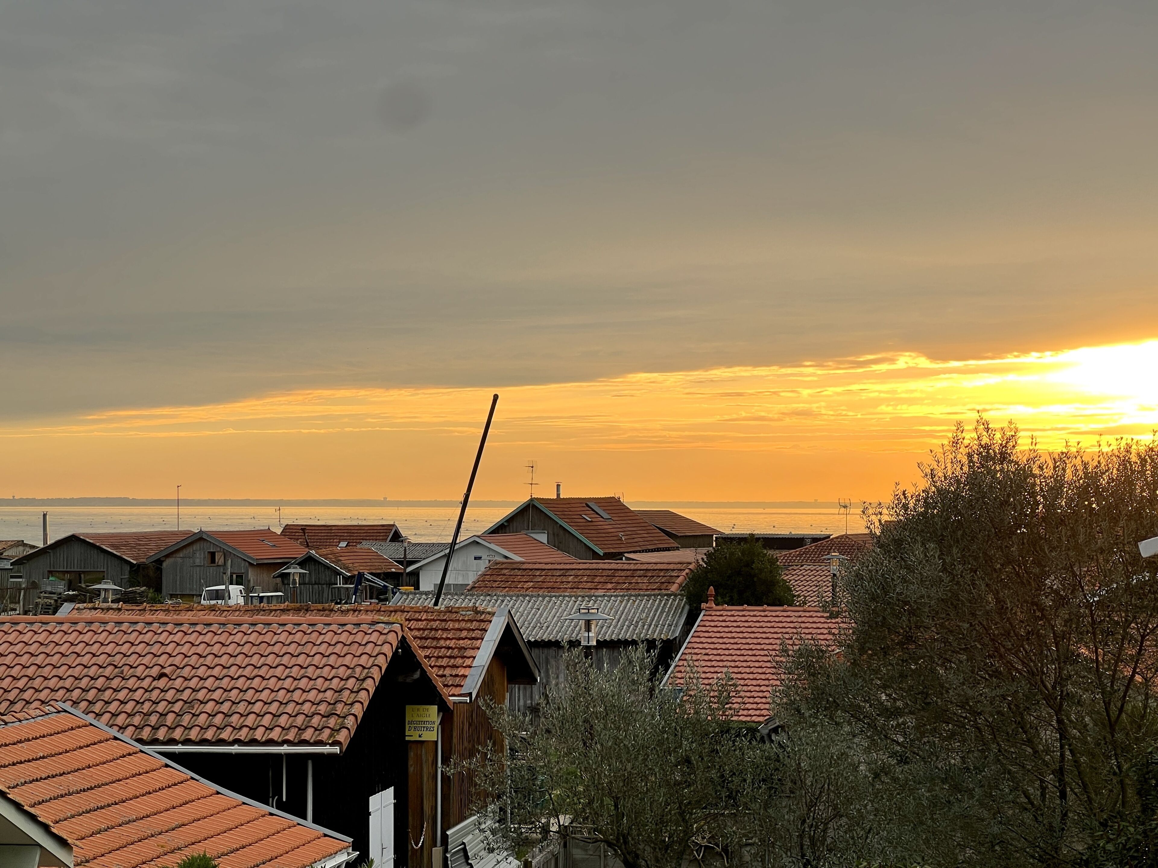 Un pueblo costero con tejados rojos tradicionales y una vista despejada del mar al atardecer.
