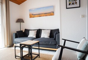 A living room with a grey sofa, a small wooden table, and a lamp. - Villa La Conche with a view of the Bassin, 2 bedrooms, comfortable, beautiful view (Lège-Cap-Ferret)