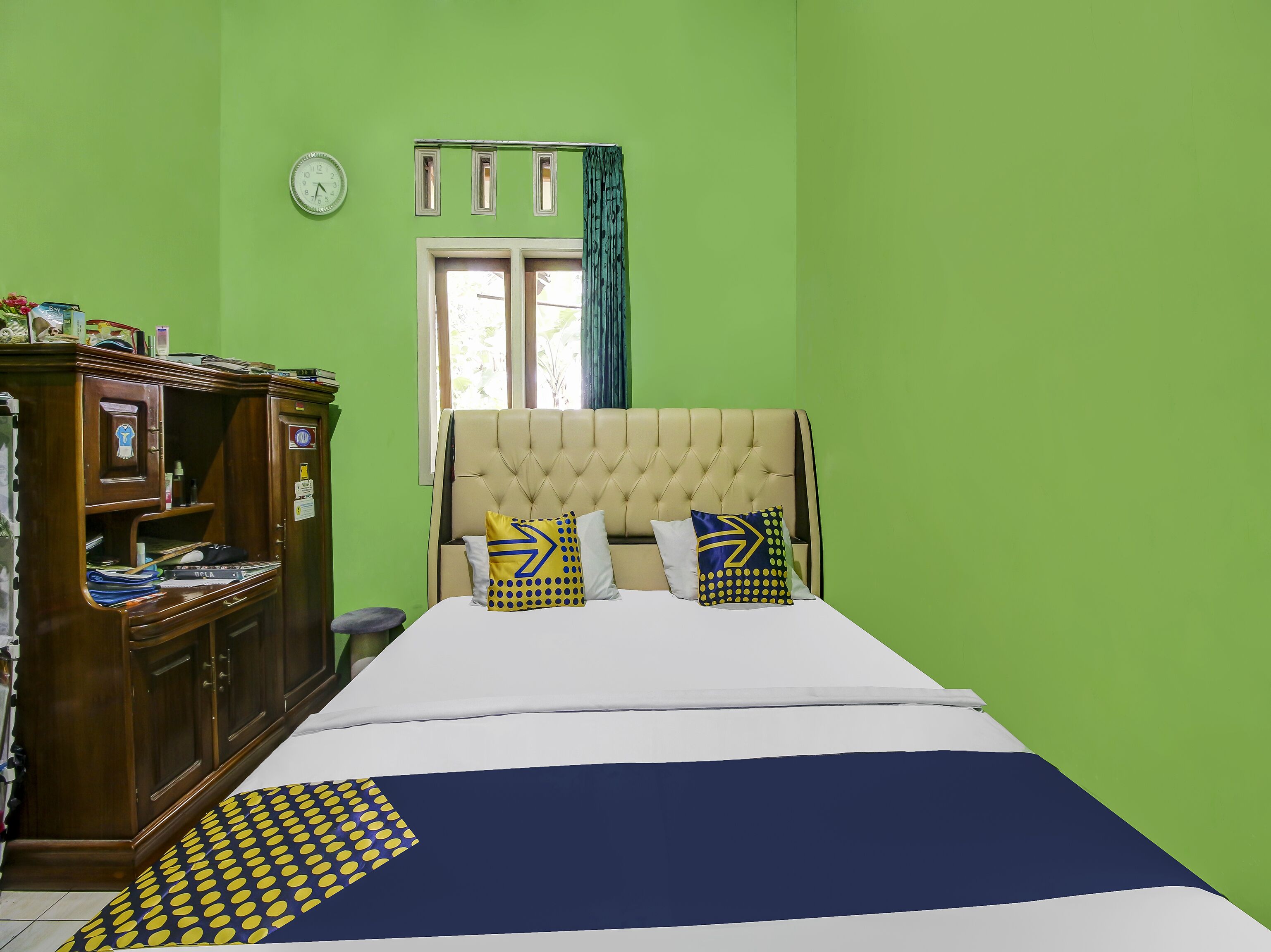 Een slaapkamer met een bed, een kledingkast, een klok en een raam met gordijnen.