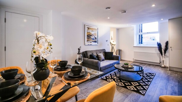 Una sala moderna con sofá, mesa de centro y comedor con mesa lista para una comida.