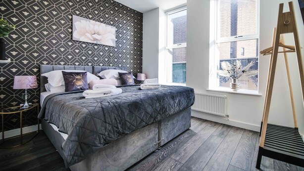 A bedroom with a bed, a window, and a radiator. - 1 Bedroom apartment with an open plan kitchen, diner, and lounge. (York)