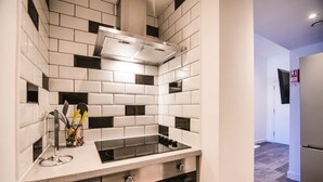 A modern kitchen with white and black tiles, a stainless steel range hood, and a built-in oven. - 1 Bedroom apartment with an open plan kitchen, diner, and lounge. (York)