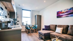 A modern kitchen with a dining area, a sofa, and a painting on the wall.
