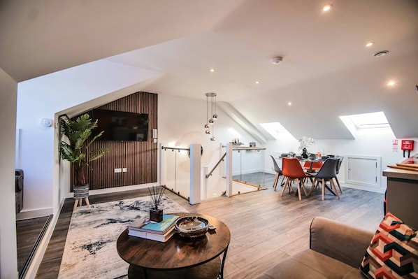 A modern loft apartment with a dining area, a staircase, and a living space.