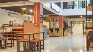 A modern restaurant with wooden tables and benches, a brick column, and a sign indicating a smoking area. - Collection O 91226 M'kostel Syariah (Sindangheula)