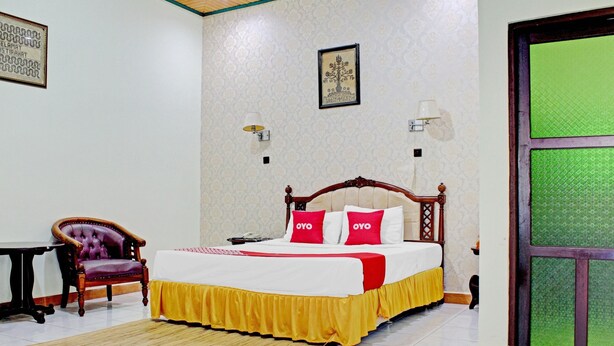 A bedroom with a bed, a chair, a table, and a door.
