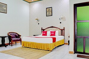 A bedroom with a bed, a chair, a table, and a door.