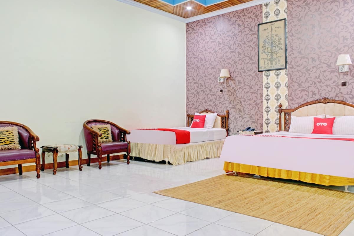 Ein Hotelzimmer mit zwei Betten, einer Sitzecke mit Stühlen, einem kleinen Tisch und einer Wandverzierung.