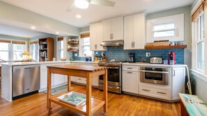 Una cocina moderna con armarios blancos, electrodomésticos de acero inoxidable y una mesa de madera.