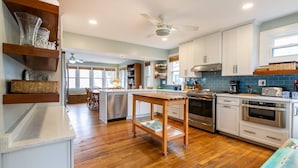 Una cocina moderna con armarios blancos, electrodomésticos de acero inoxidable y una mesa de comedor de madera.