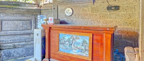 A reception area with a wooden desk, a framed painting, a water dispenser, and a stone wall.