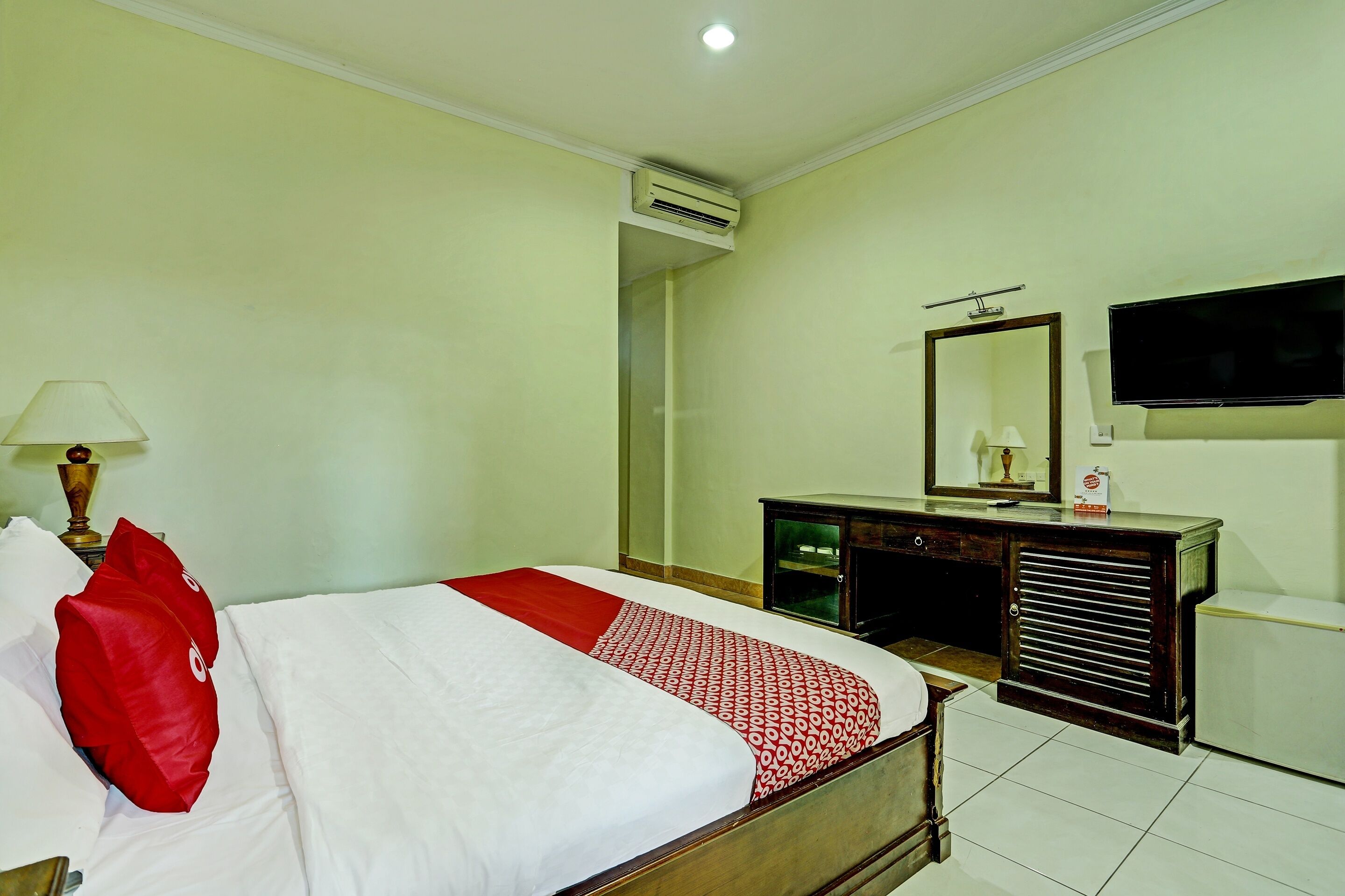 A hotel room with a bed, a dresser, a television, and an air conditioning unit.