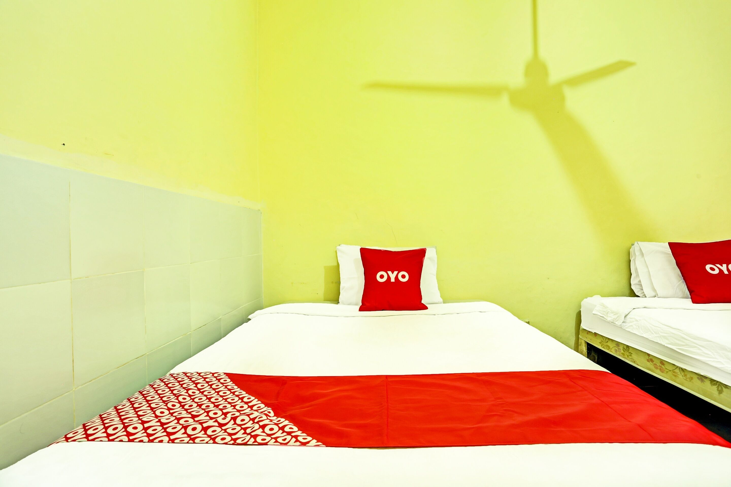 A room with two beds, each with a red pillow labeled "OYO".