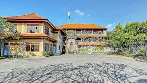 Un edificio tradicional con tejado de tejas, entrada central y jardín circundante.