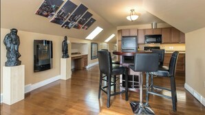 A spacious kitchen with modern appliances, a dining area with bar stools, and artwork on the walls. - Unique spacious upper Condo Suite. Steps from waterfront  (Sarnia)
