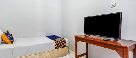 A room with a white sofa, a television on a wooden table, and a patterned cushion.
