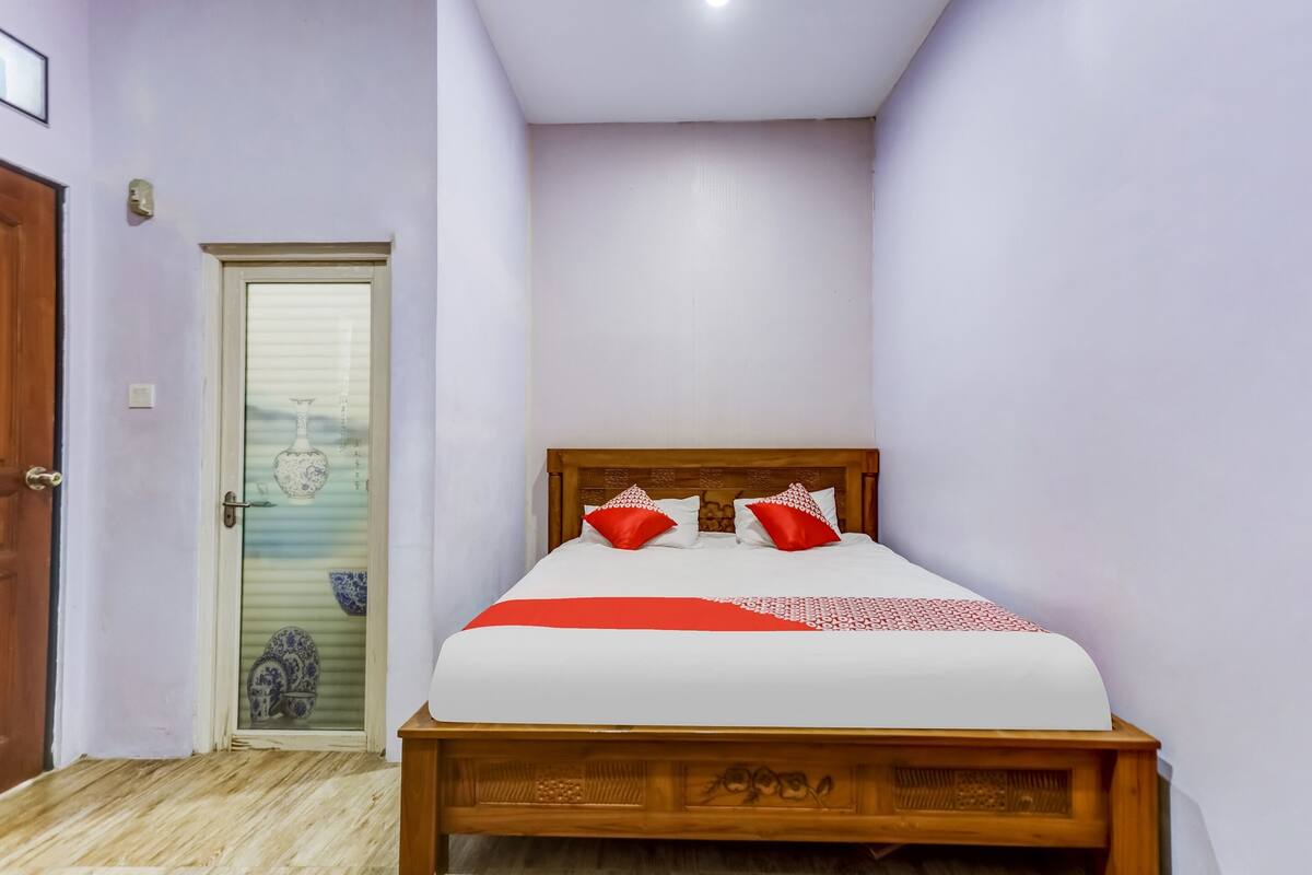 A bedroom with a wooden bed, a door with a glass panel, and a small decorative item on the floor.