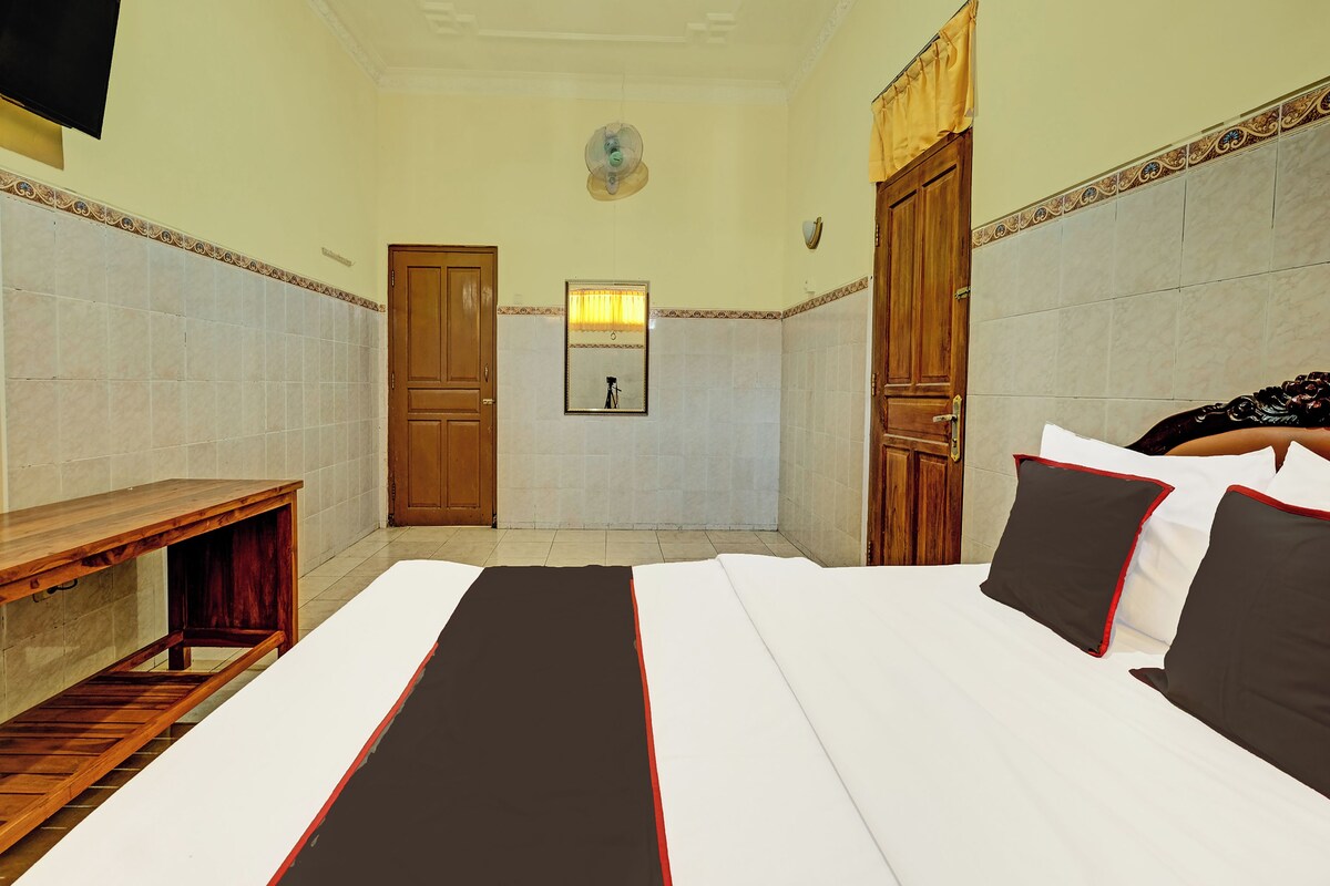 Ein Hotelzimmer mit einem Bett, einer hölzernen Bank, einem Spiegel und zwei Türen.