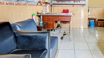A waiting area with a black leather sofa, a wooden desk with a telephone, and a chair.