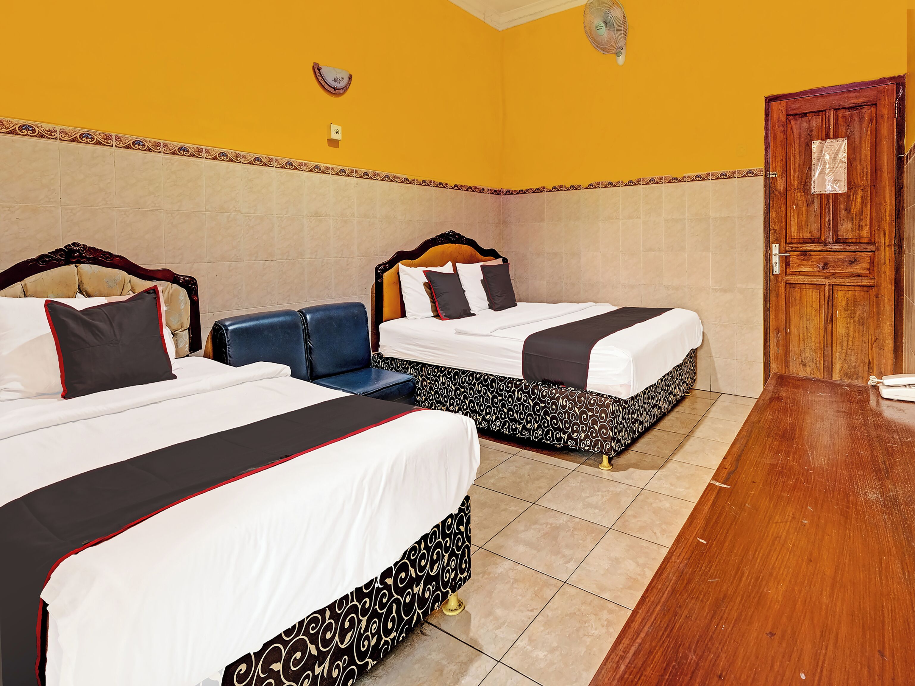 A hotel room with two beds, a wooden door, and a tiled floor.