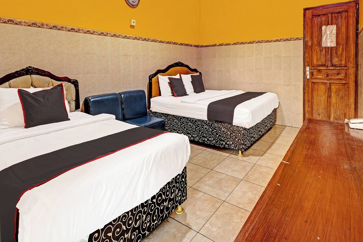 A hotel room with two beds, a wooden door, and a tiled floor.