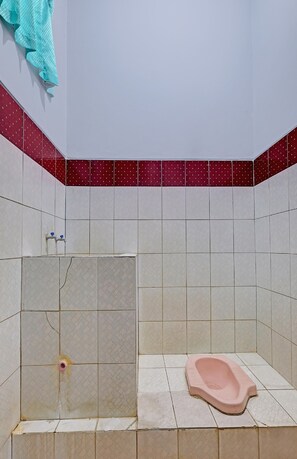 Et badeværelse med toilet, håndvask og bruseområde.