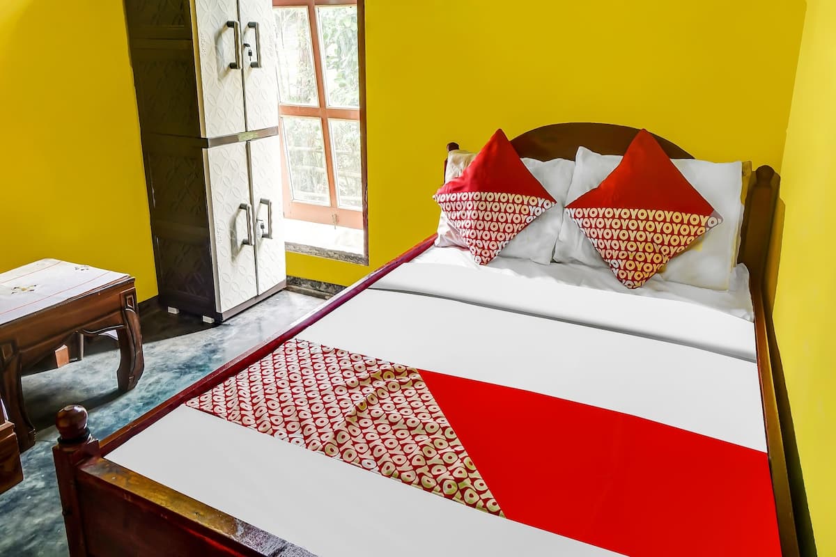Un lit avec une couvre-lit à motifs, une tête de lit en bois et deux oreillers à motifs rouges et blancs.