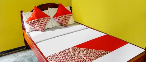 A bed with a white and red bedspread, two red pillows, and a wooden headboard.
