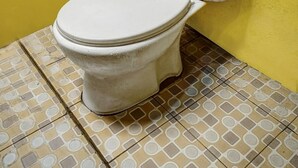 A toilet in a bathroom with yellow walls and patterned tile flooring. - Hotel O Kampung Wisata Ekologi Puspa JagadNearGunung Kelud (Gandusari)