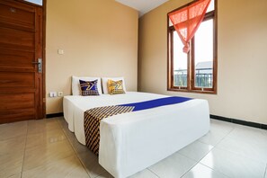 A hotel room with a large bed, two pillows, a blue throw, and a window with a red curtain. - OYO Homes 91008 Eco Tourism Desa Cibodas Babakan Gentong 1 Syariah (Lembang)