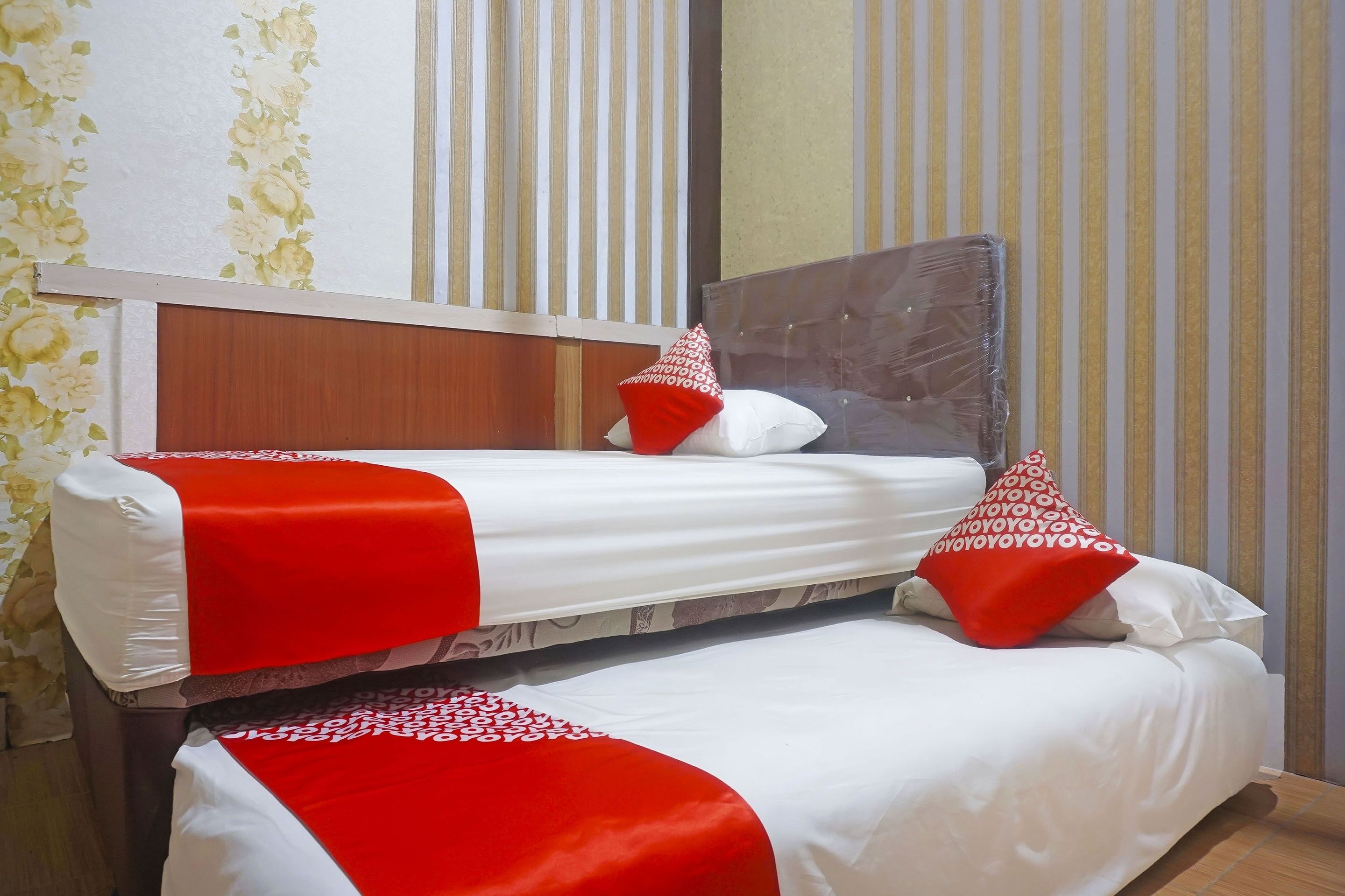 A hotel room with two beds, each with white bedding and red accents.