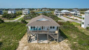 Une maison située en bord de mer, dotée d’un porche couvert et offrant une vue sur l’océan.