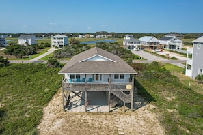 A beachfront house with a covered porch and a view of the ocean.