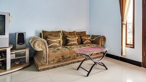A living room with a sofa, a small table, a television, and a speaker. - OYO Homes 91009 Eco Tourism Desa Cibodas Areng 4 Syariah (Lembang)