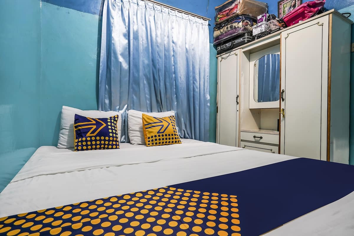 A bed with a blue and yellow polka dot bedspread, two pillows with arrow designs, and a white headboard.